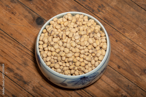 Soybeans placed in a bowl or plate are on the wood grain table