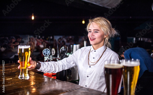 Experienced girl bartending demonstrates his professional skills while standing near the bar counter in bar photo