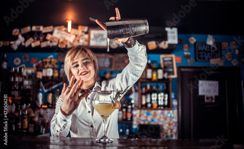 Focused girl bartender surprises with its skill bar visitors in cocktail bars photo