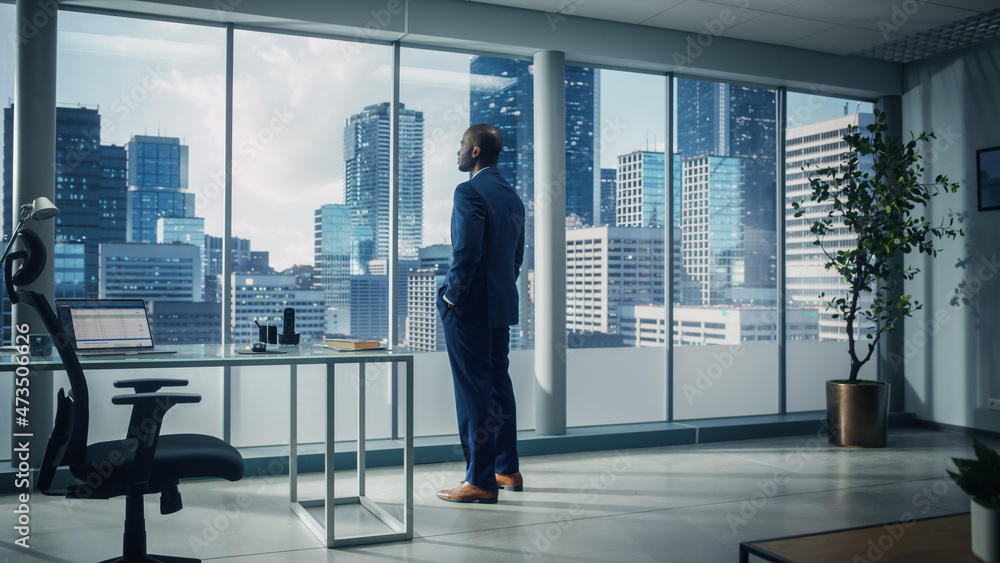 Thoughtful African-American Businessman in a Perfect Tailored Suit Standing in His Office Looking out of the Window on Big City. Successful CEO Planning His Investment Strategy for e-Commerce Startup - obrazy, fototapety, plakaty 