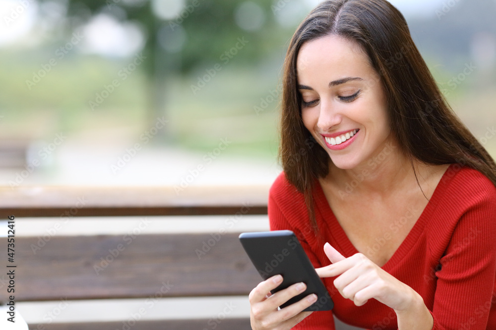 Happy woman browsing phone content on a bench Happy woman browsing phone content on a bench