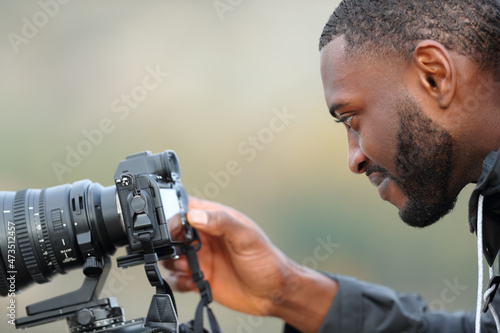 Man with black skin checking photos on mirrorless camera photo