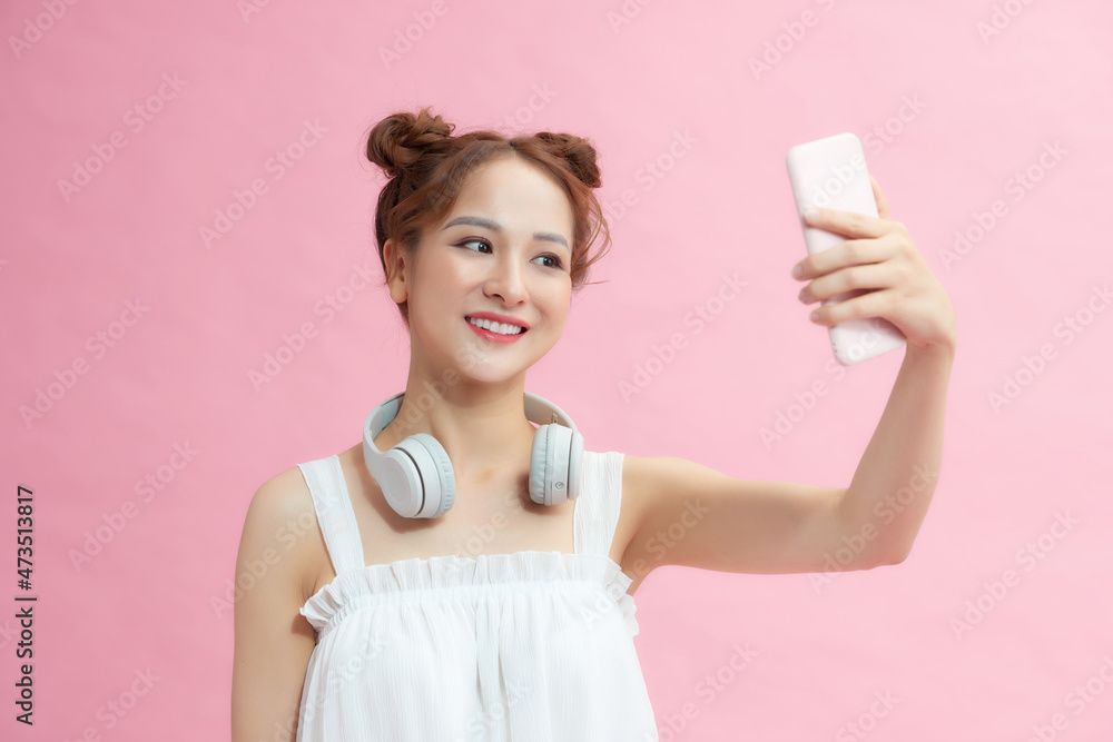 Portrait of charming young woman smiling while taking selfie photo isolated over pink background Portrait of charming young woman smiling while taking selfie photo isolated over pink background