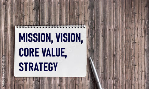 MISSION, VISION, CORE VALUE, STRATEGY A symbol of our core values. Conceptual words on notepad on wooden background. Business concept and our core values.