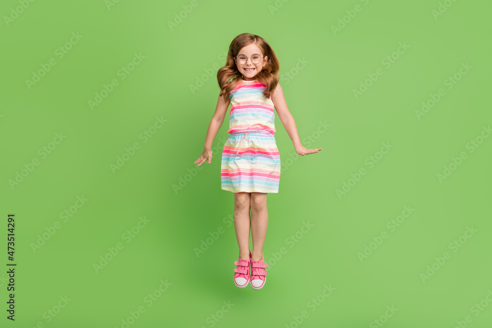 Full length body size photo small girl jumping up cheerful isolated pastel green color background Full length body size photo small girl jumping up cheerful isolated pastel green color background