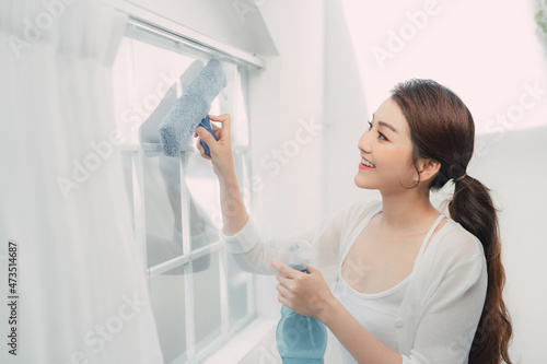 Young woman cleaning window at home