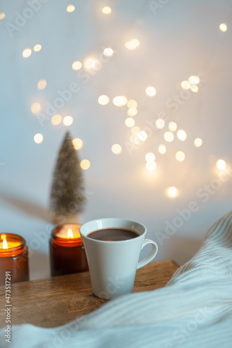 new year christmas card. Christmas tree, lights of garlands, two lighted candles and a cup of coffee. comfort and hygge