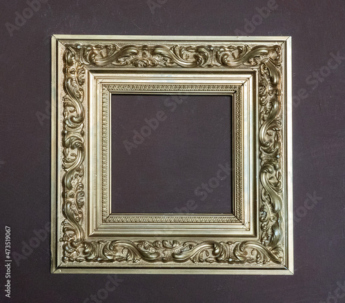 Photo of golden frames for paintings and photos on a purple wall. Interior and abstraction