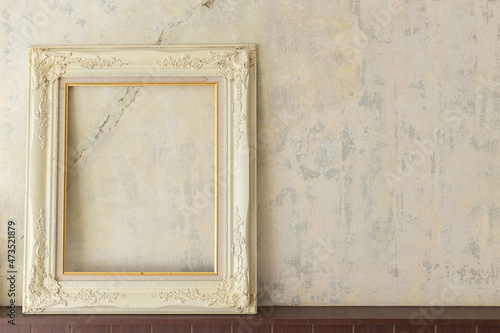 An old white wooden picture frame is placed on an old cracked concrete wall.