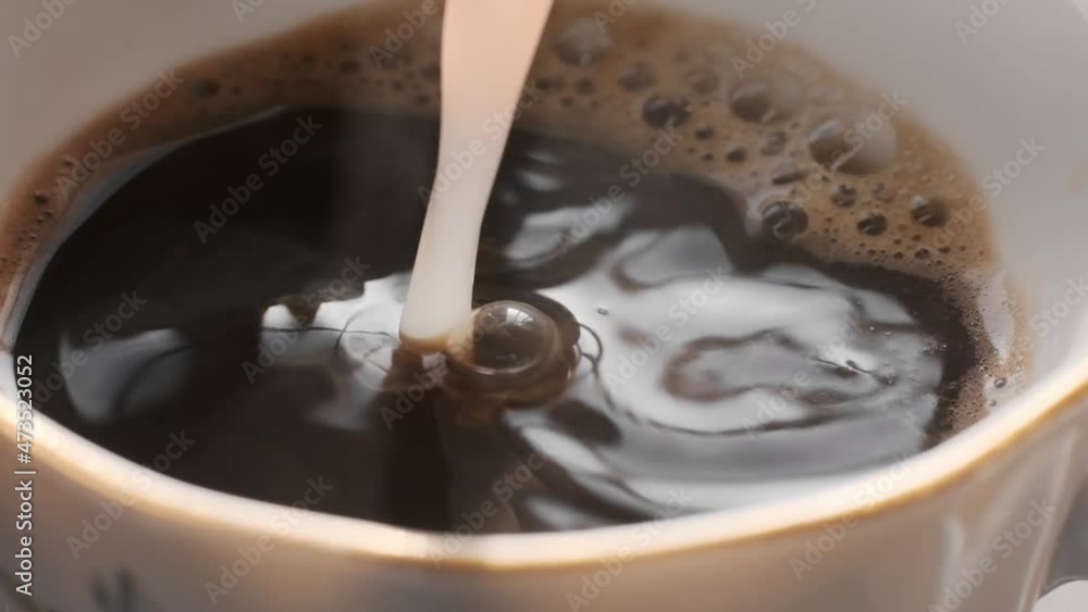 hot coffee in cup with milk being poured in hot coffee in cup with milk being poured in