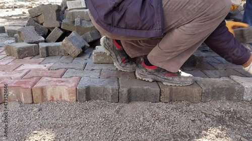  Construction worker laying paving slabs on the street. 