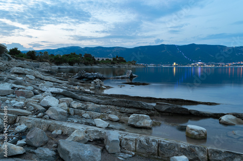 Rocky coast by the sea in the evening and blue sky with mountains.