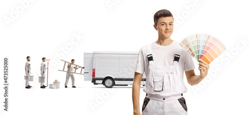 Decorator holding a color swatch palette and other housen painters behind with a van photo