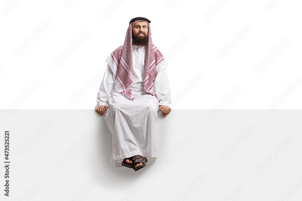 Saudi arab man sitting on a blank panel and looking at camera - obrazy, fototapety, plakaty 