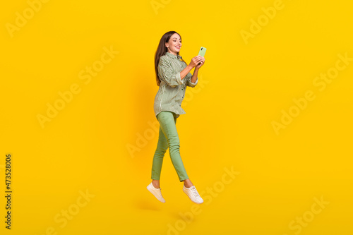 Full size profile side photo of young lady use cellphone post comment connection 4g jump isolated over yellow color background