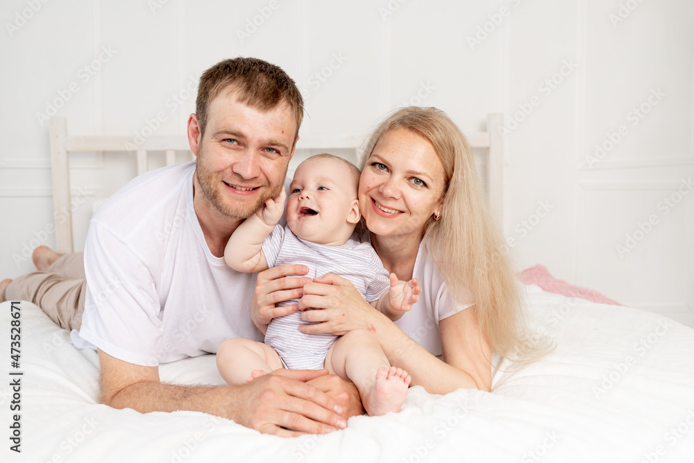 happy family mom, dad and baby play on the bed at home and have fun happy family mom, dad and baby play on the bed at home and have fun