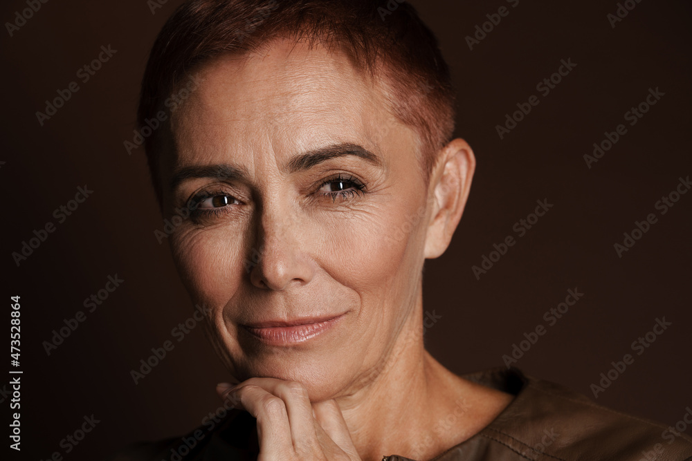 Obraz premium Senior ginger woman with short hair posing and looking aside