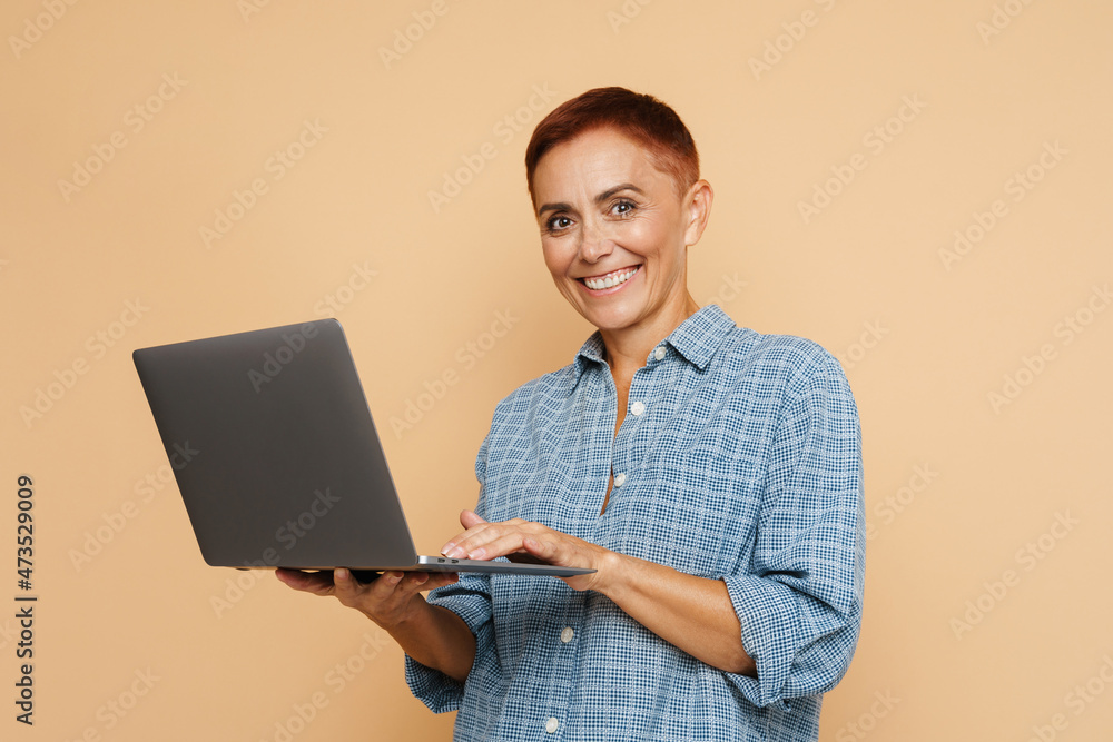 Senior ginger woman smiling while posing with laptop Senior ginger woman smiling while posing with laptop