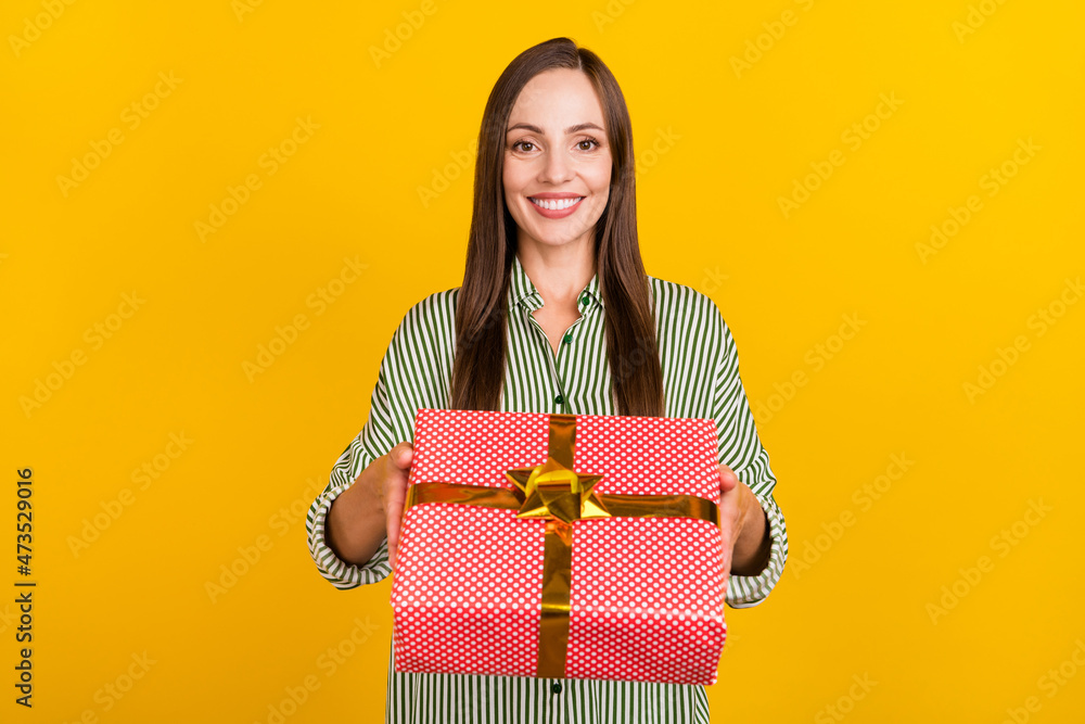 Photo of young cheerful lovely woman good mood hold present box isolated over yellow color background Photo of young cheerful lovely woman good mood hold present box isolated over yellow color background