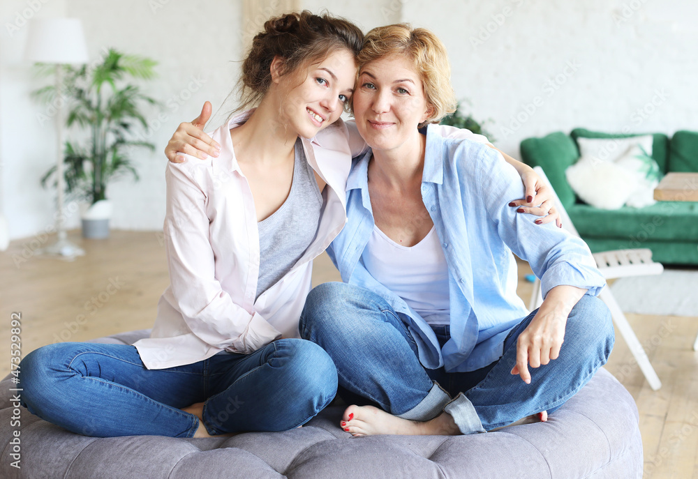 Beautiful senior mom and her adult daughter are hugging, looking at camera and smiling. At Home. Beautiful senior mom and her adult daughter are hugging, looking at camera and smiling. At Home.