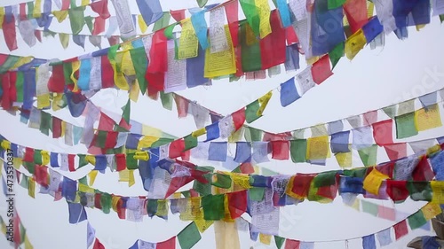 Long strings of colorful Tibetan prayer flags flutter in the wind somewhere in high foggy mountains in Nepal.