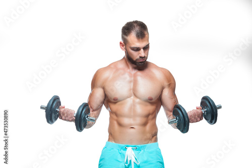 Sexy athletic man is showing muscular body with dumbbells standing with his head down, isolated over white background