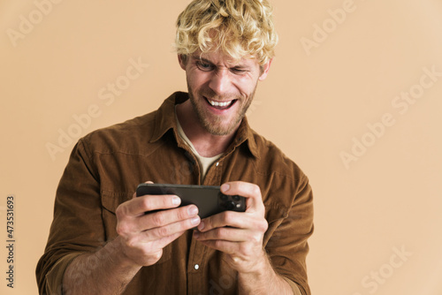 White blonde man wearing shirt playing online game on cellphone © Drobot Dean