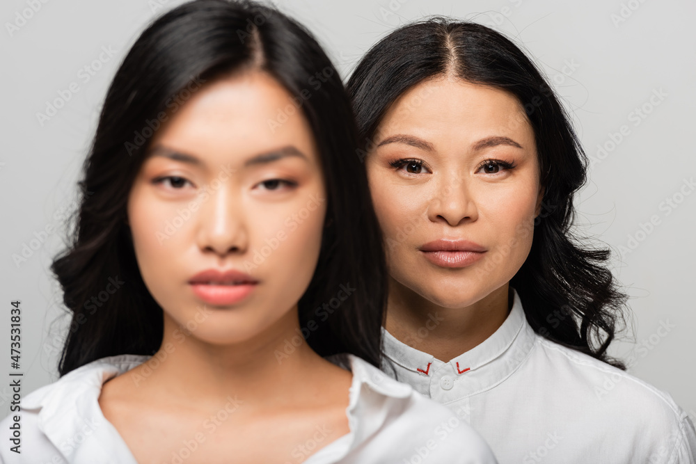 blurred young adult daughter near asian mother standing behind isolated on grey blurred young adult daughter near asian mother standing behind isolated on grey