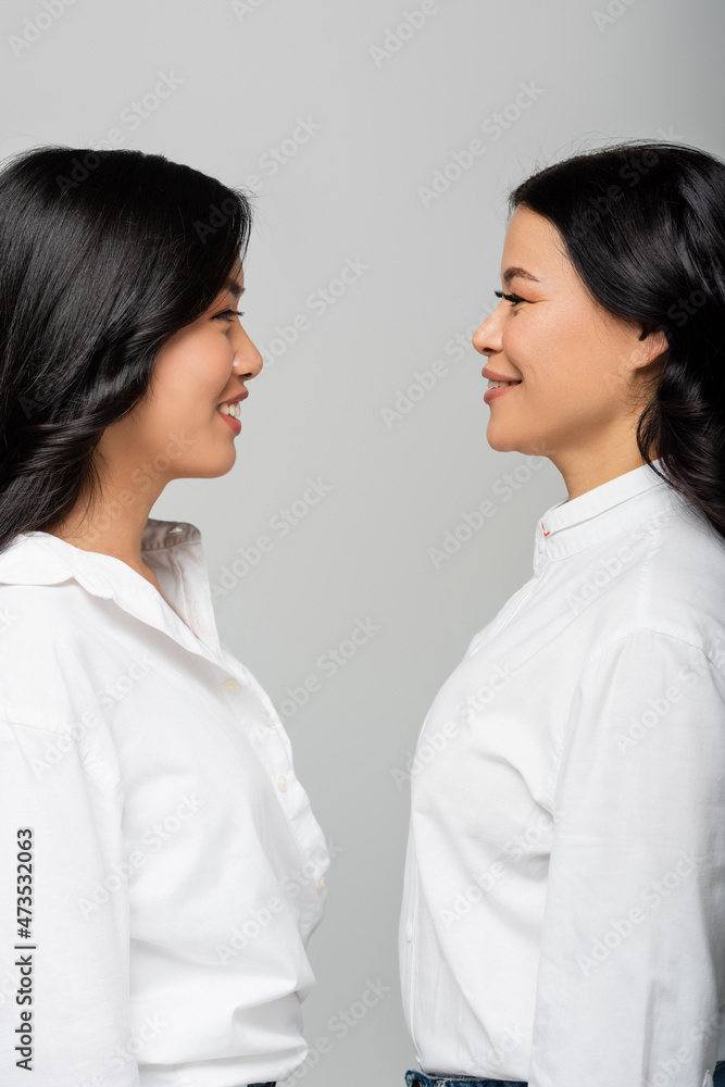 side view of happy asian mother looking at cheerful young adult daughter isolated on grey side view of happy asian mother looking at cheerful young adult daughter isolated on grey