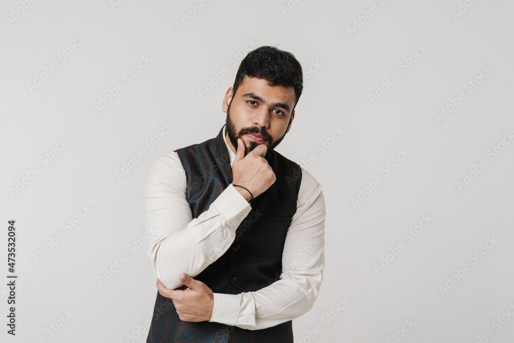 Bearded south asian man holding his chin and looking at camera Bearded south asian man holding his chin and looking at camera