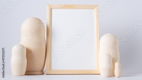 Bild auf Leinwand Children's toy wooden matryoshka doll and mockup frame on white background