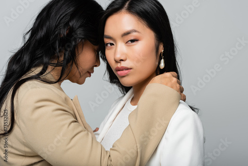 asian mother embracing young daughter isolated on grey © LIGHTFIELD STUDIOS