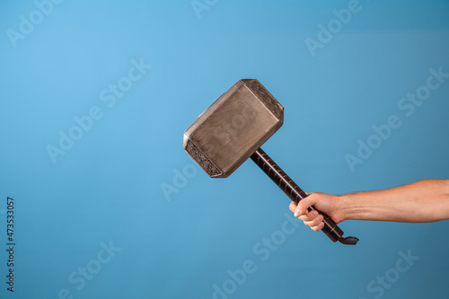 Be a hero, perform a feat. The Scandinavian hammer of Thor, Mjolnir in a man's hand. Photo on a blue background photo