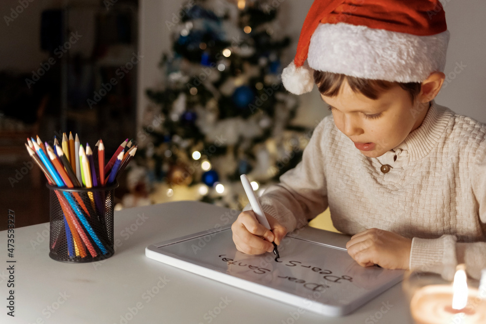 Little boy writing the letter to Santa. Child dreams of a gift that he can receive. The child writes a letter to Santa Claus. People and Holiday concept. Little boy writing the letter to Santa. Child dreams of a gift that he can receive. The child writes a letter to Santa Claus. People and Holiday concept.