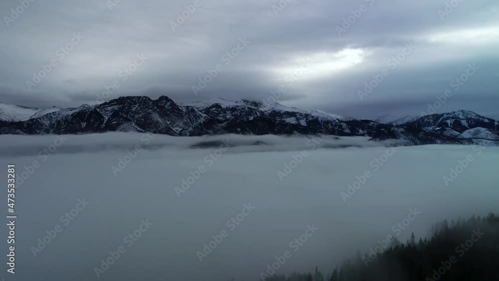 Aerial view of mountains covered with snow. Foggy and dark winter day in the Tatra mountains. Fog in the mountain valley and cold and dark view of high mountain range. Aerial view of mountains covered with snow. Foggy and dark winter day in the Tatra mountains. Fog in the mountain valley and cold and dark view of high mountain range.