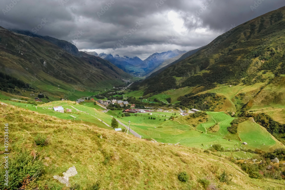 View from the Swiss Furka pass on the town of Realp in the canton of Uri. On the horizon the Oberalppass where the weather deteriorates View from the Swiss Furka pass on the town of Realp in the canton of Uri. On the horizon the Oberalppass where the weather deteriorates