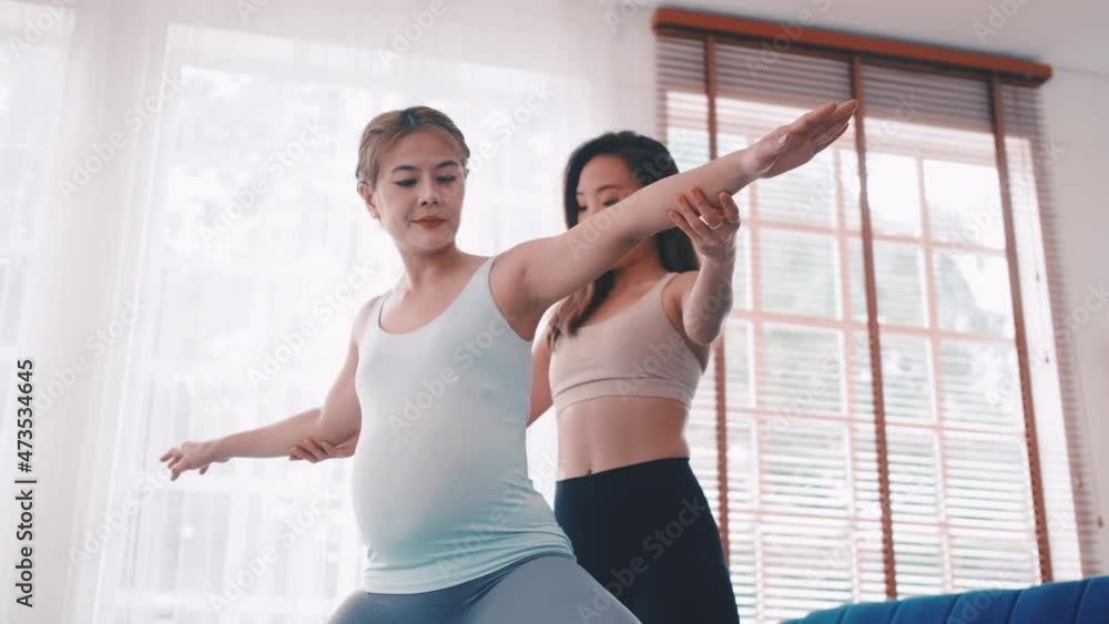 Pregnant woman doing Pilates exercise with personal trainer at home. Pregnant woman doing Pilates exercise with personal trainer at home.