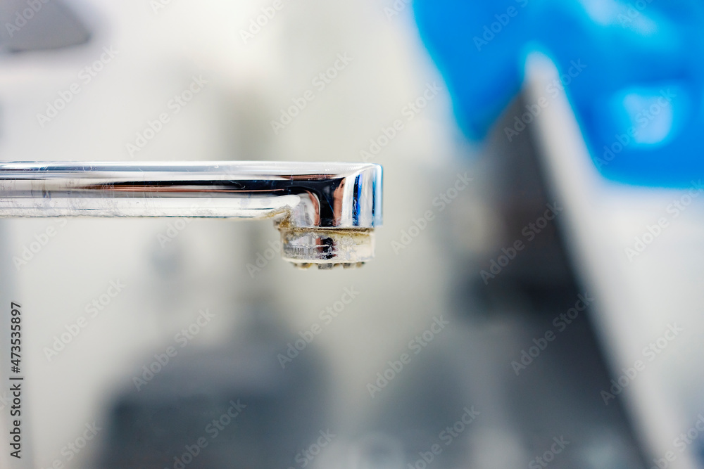 Polluted water and tap. Close up of a tap with limescale and polluted water. Polluted water and tap. Close up of a tap with limescale and polluted water.