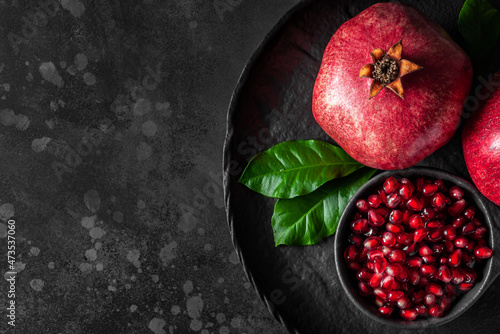 Pomegranate on dark background, top view, low key, horizontal, copy space