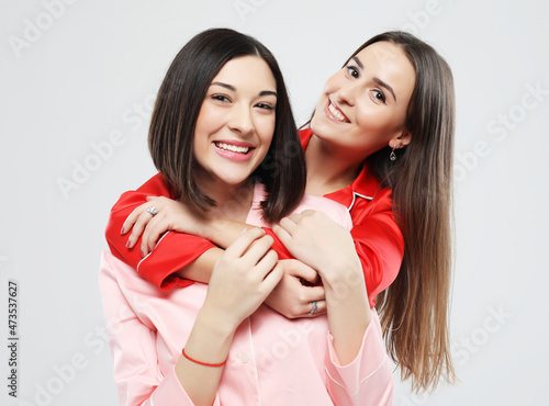 lifestyle  friendship and people concept - two beautiful girls dressed in pajamas hugging and smiling