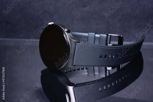 Smart watch on a mirror surface on a dark background, close-up