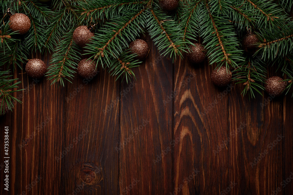 Christmas background with baubles and fir branches on dark wooden board. Top view. Copy space. Xmas decoration