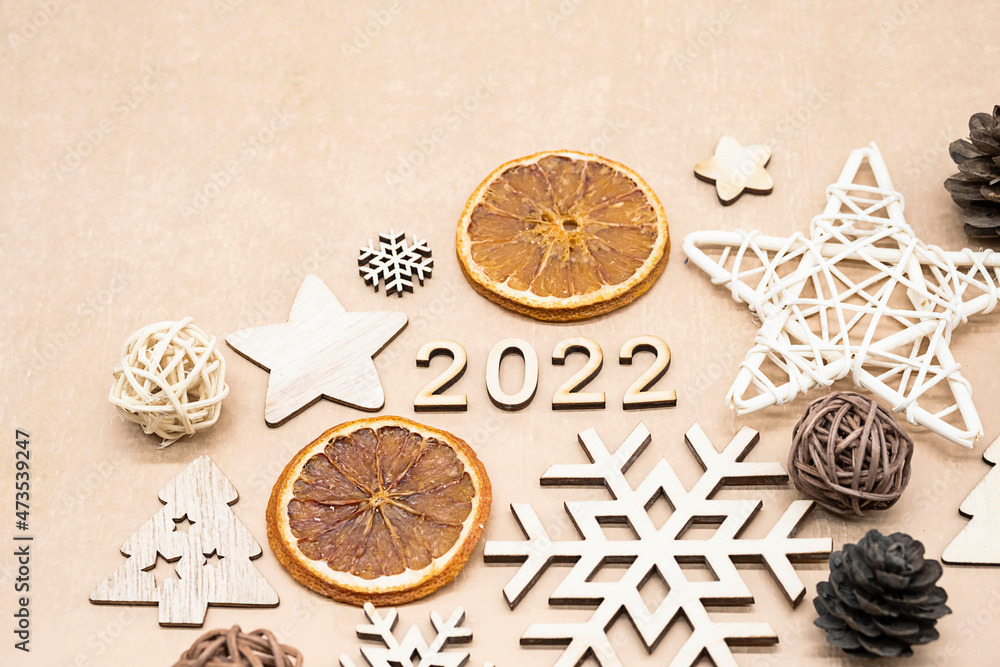 New year composition numbers 2022, wooden decorations, fir and pine cones, dried slices of oranges. Festive Christmas concept in eco style on beige background.