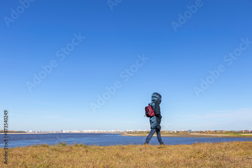 A woman on the shore of the bay looks at the city, which is in the distance. Calm and tranquility.