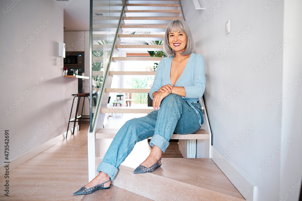 Smiling mature woman sitting on staircase at home Smiling mature woman sitting on staircase at home