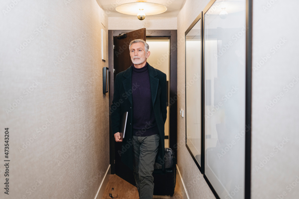 Mature businessman with laptop entering in hotel room Mature businessman with laptop entering in hotel room