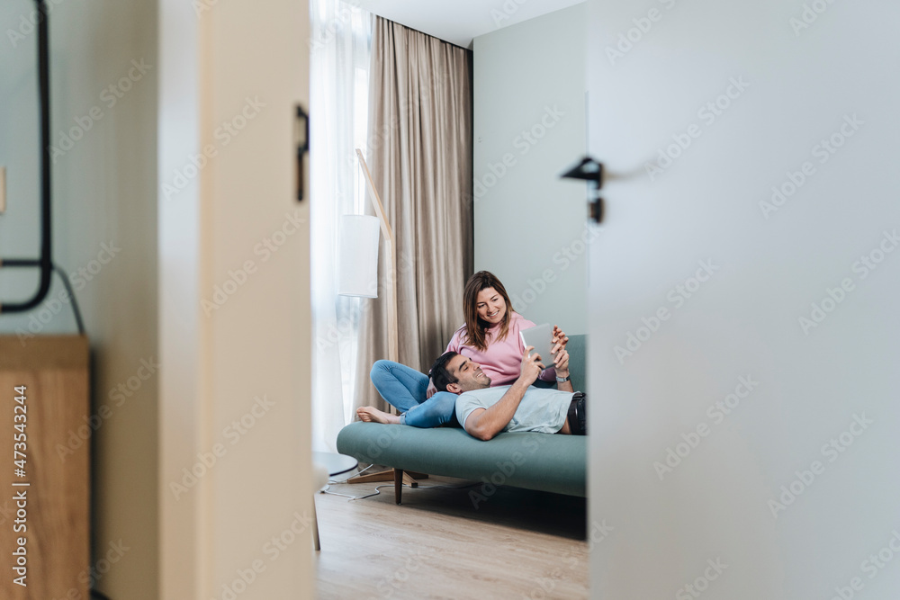 Man using digital tablet while lying on woman lap in hotel room Man using digital tablet while lying on woman lap in hotel room