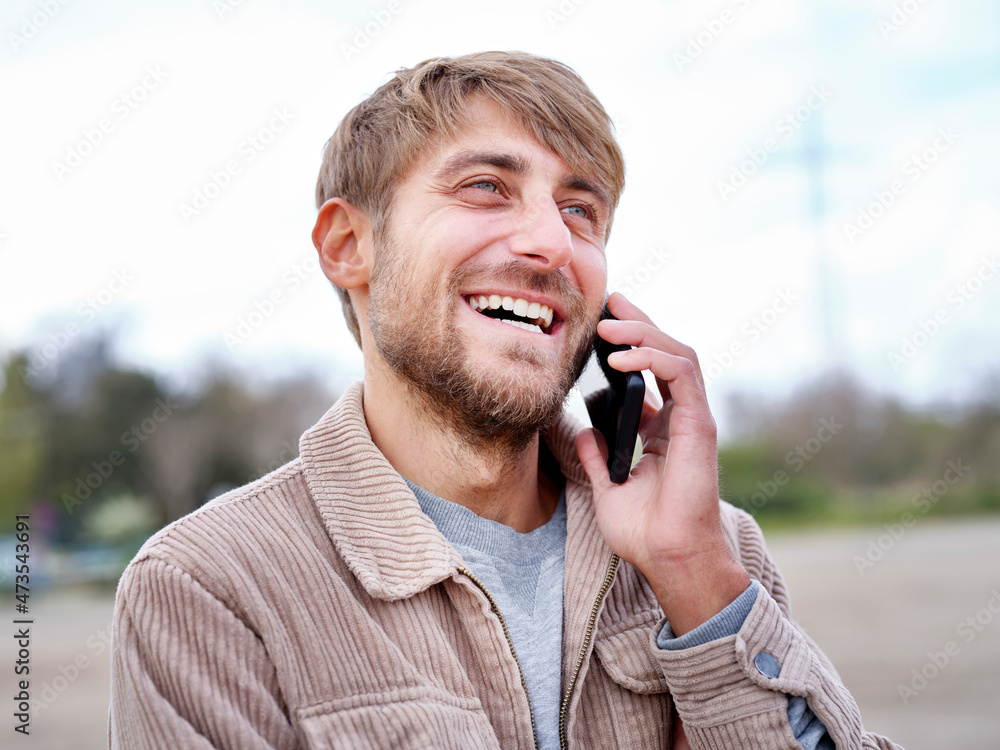 Happy bearded man looking away while talking on smart phone Happy bearded man looking away while talking on smart phone