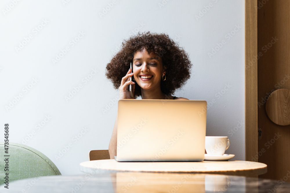 Female university student talking on mobile phone while sitting at cafe Female university student talking on mobile phone while sitting at cafe