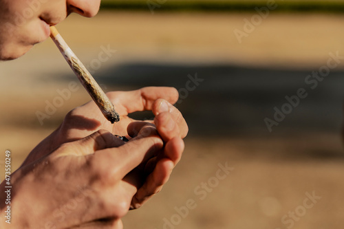 Teenage boy igniting marijuana joint during sunset photo